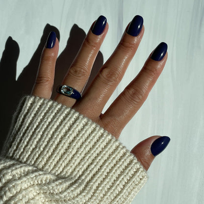 OMG - Press-On | Short | Round showing hand with glossy deep indigo short round press-on nails against white background