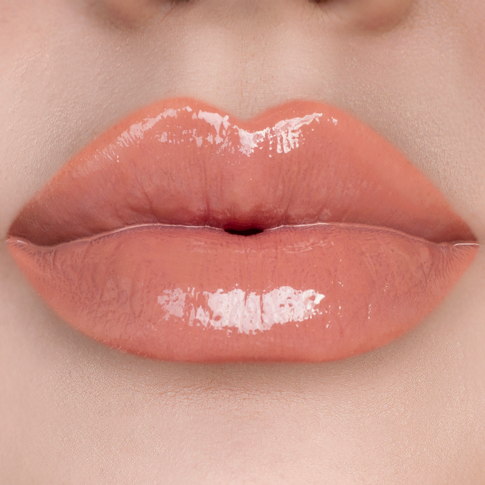 Overqualified peachy nude lip gloss on lips, light skin tone