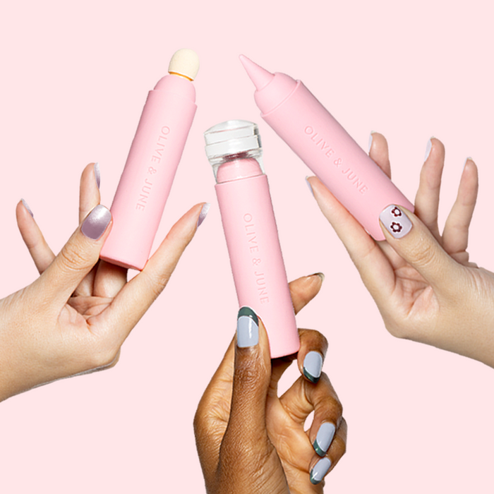 Three hands holding pink Penny Nail Art Tool silicone manicure devices with varied nail polish shades and flower design nails