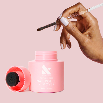 Polish Remover Pot + Clean Up Brush showing hand holding brush above pink remover jar with foam applicator on blush background