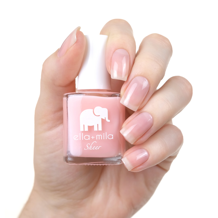 Pure sheer pink peach nail polish manicure on a light skin tone with the bottle