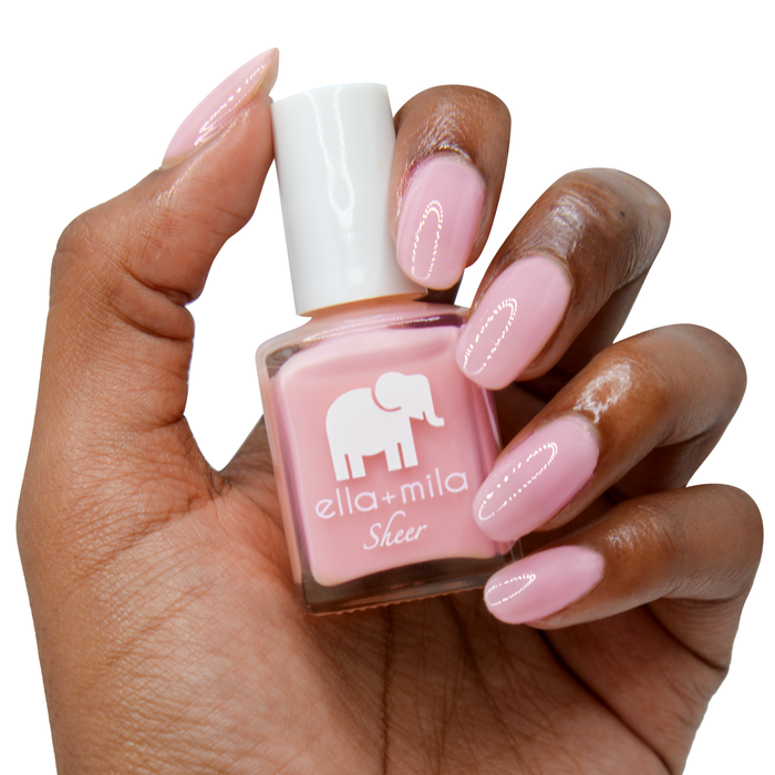 Pure sheer pink peach tint nail polish on a deep skin tone, hand holding the bottle