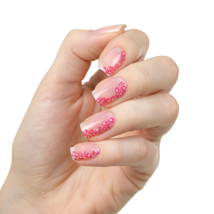 Pure sheer peach nail polish with pink polka dot accent nails on a light skin tone
