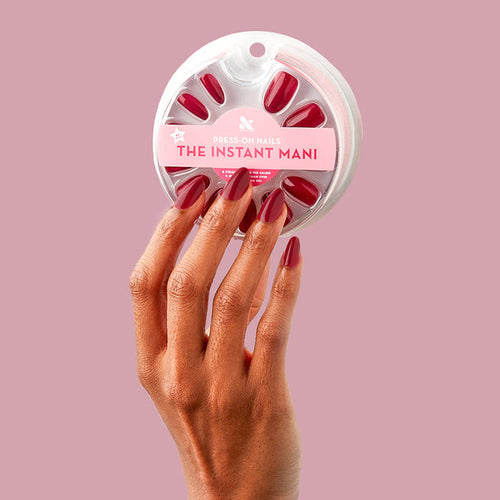SC - Press-On | Medium | Oval hand holding packaging with medium oval deep bordeaux press-on nails manicure