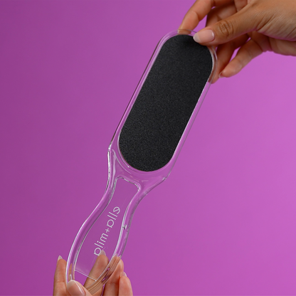 Hand holding the dual-sided foot file on a purple background