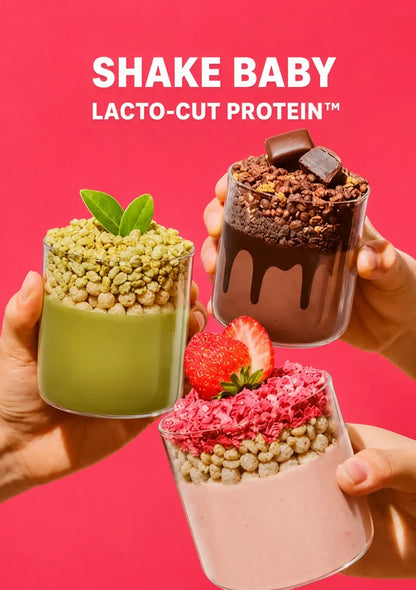 Three hands hold up three different protein shake parfaits against a bright pink background with the text 'SHAKE BABY LACTO-CUT PROTEIN' at the top. The left shake is green with green flakes and a mint leaf, the middle-right shake is dark brown chocolate with chocolate drizzle and a chocolate piece, and the bottom shake is light pink with pink flakes and a strawberry.