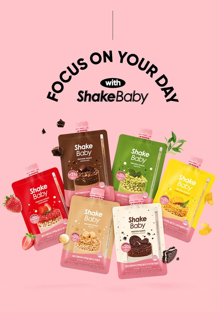 Six ShakeBaby snack pouches in assorted flavors are arranged on a pink background with promotional text reading 'FOCUS ON YOUR DAY with ShakeBaby'. The pouches include red strawberry, dark chocolate brown, green mango, yellow citrus, and white chocolate flavors, with small fruit and candy illustrations around them.
