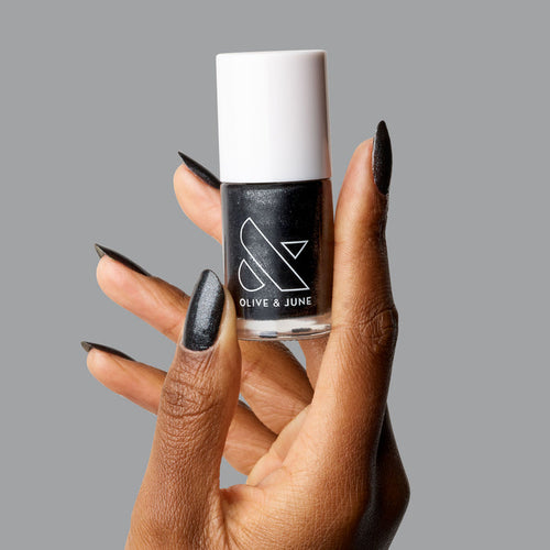 Hand holding SPACEY nail polish bottle showing black shimmer manicure with long-lasting gel polish finish