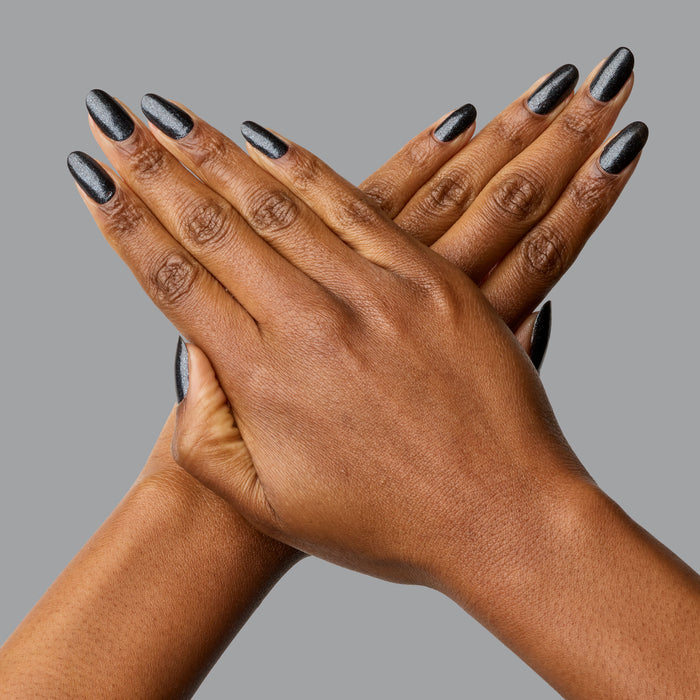 Hands with nails painted in SPACEY black shimmer polish showing a glossy, long-lasting gel manicure finish