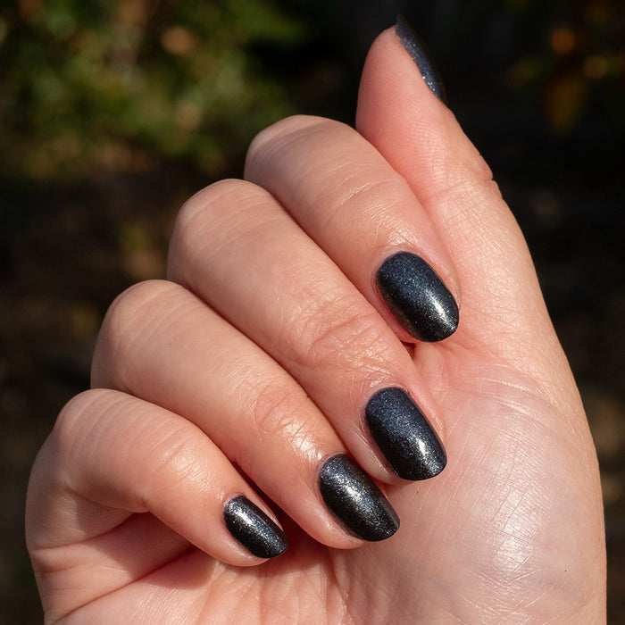 Hand with nails polished in SPACEY showing dark shimmer gel polish with a quick-dry, long-lasting manicure finish