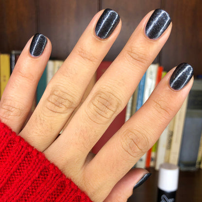 Hand with nails painted in SPACEY showing glossy black polish with starry shimmer and durable gel manicure finish
