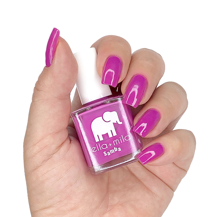 Staycation Vacation fuchsia nail polish on a medium skin tone, hand holding the bottle