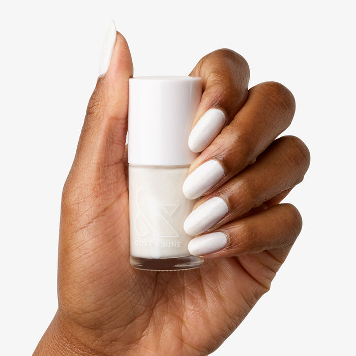 Hand with nails painted in STELLAR white polish holding a matching bottle for a smooth long-lasting manicure finish
