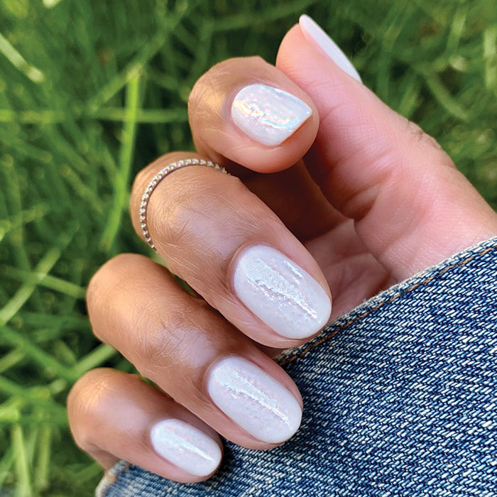 Hand with nails painted in STELLAR sparkly white polish showing smooth, long-lasting manicure with subtle shimmer detail