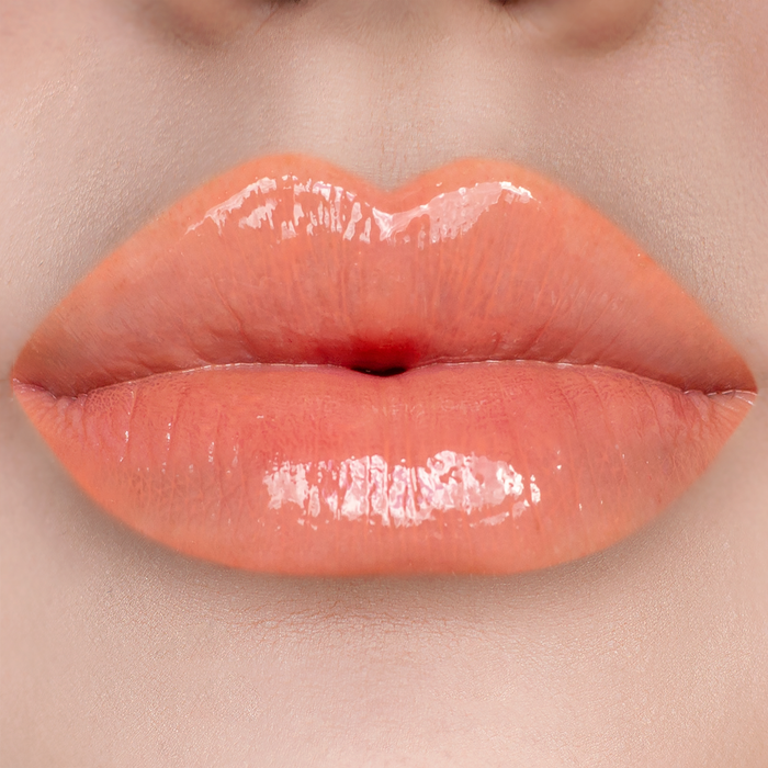 Strapless peach coral lip gloss on lips, light skin tone
