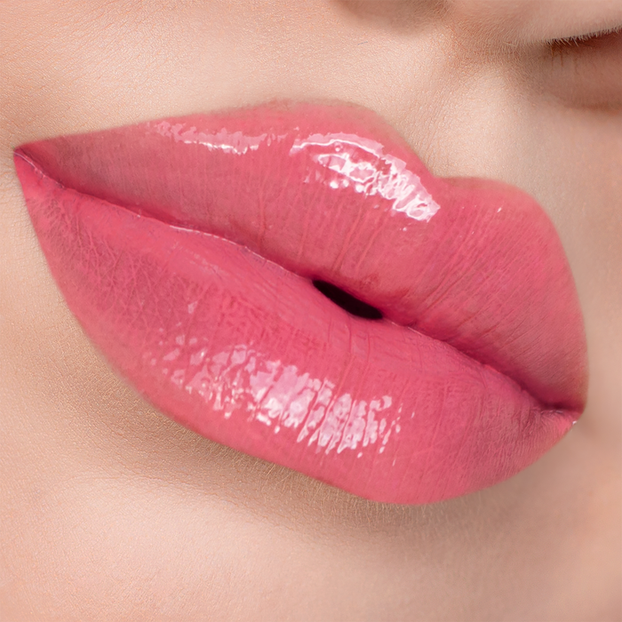Glossy Stripped coral pink lip gloss on lips, light skin tone close-up