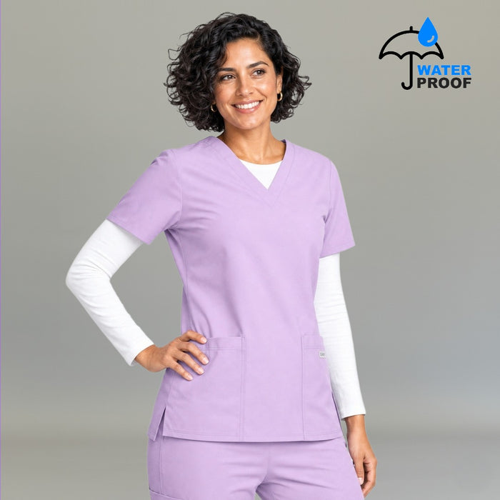 Women's lilac 502 scrub top with hand on hip layered over white underscrub — lightweight fluid-resistant nursing top S-FOR-ME