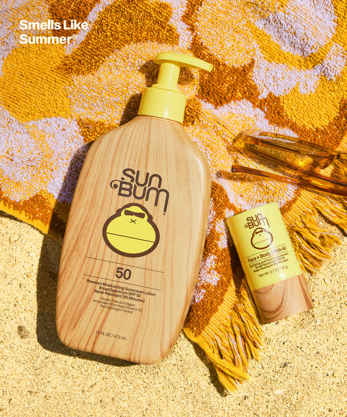 Sun Bum XL SPF 50 Lotion + Face and Body stick 40 on towel with sunglasses on sandy beach background