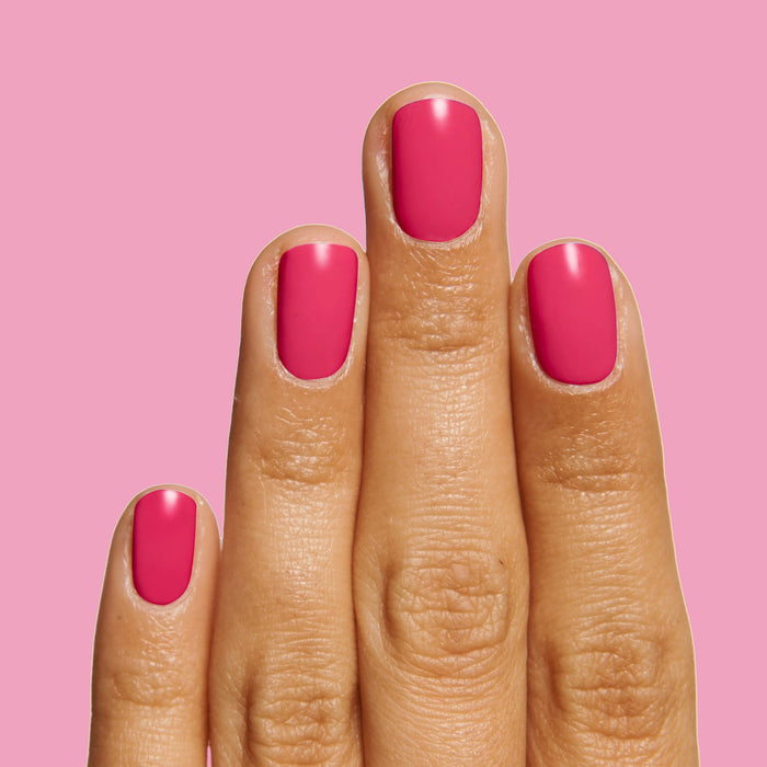 Hand with vibrant hot pink nails polished with XOXO long-lasting nail polish on a bright pink background