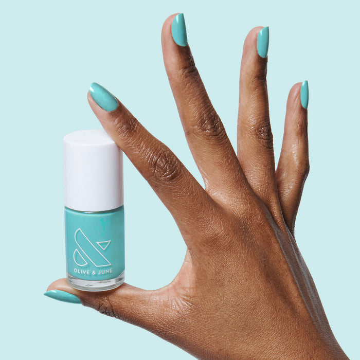 Hand with nails painted in bright turquoise using Yes Please polish for a vibrant, long-lasting manicure by Olive and June