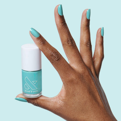 Hand with nails painted in bright turquoise using Yes Please polish for a vibrant, long-lasting manicure by Olive and June