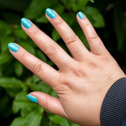 Hand showing nails painted in bright turquoise shade Yes Please for a smooth, long-lasting mani by Olive and June